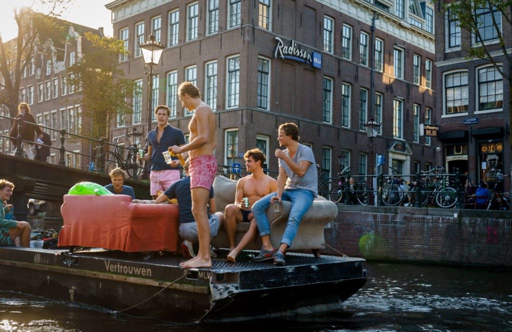 Vier mannen op een boot varen door de grachten van Amsterdam