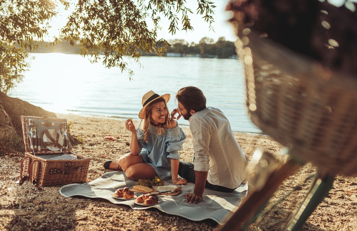 man and woman sit on sand picnic