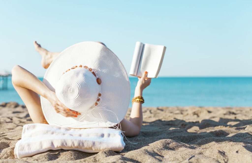 Een vrouw die op het strand een boek leest