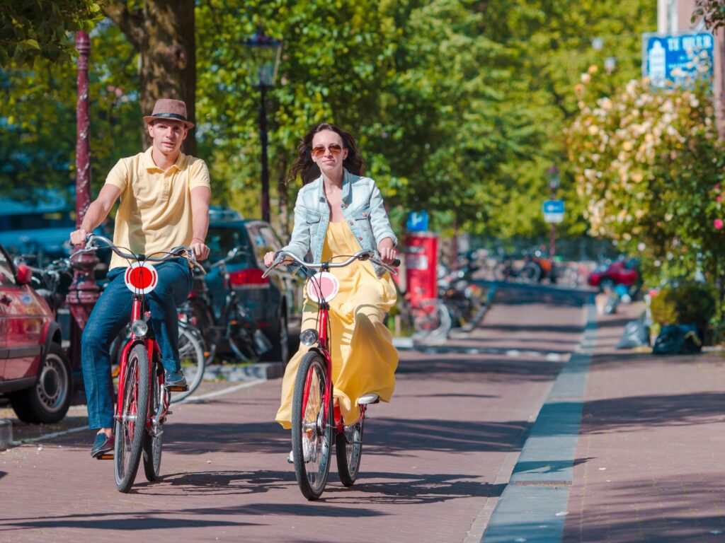 a man and woman cycle through amsterdam as a things to do in amsterdam for couples