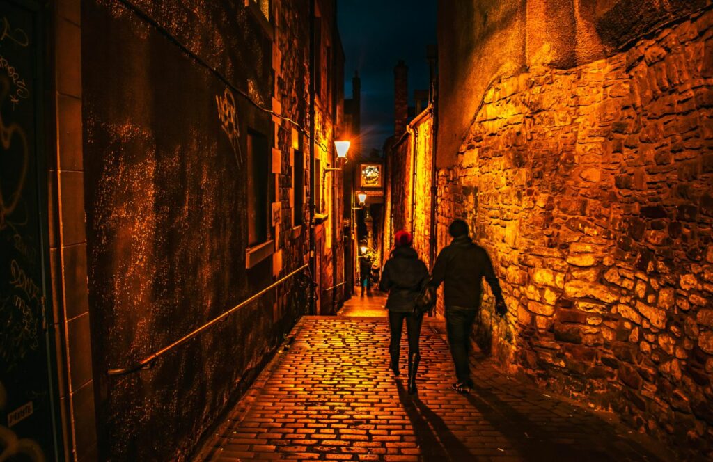 couple hand in hand walking through edinburgh old town at night