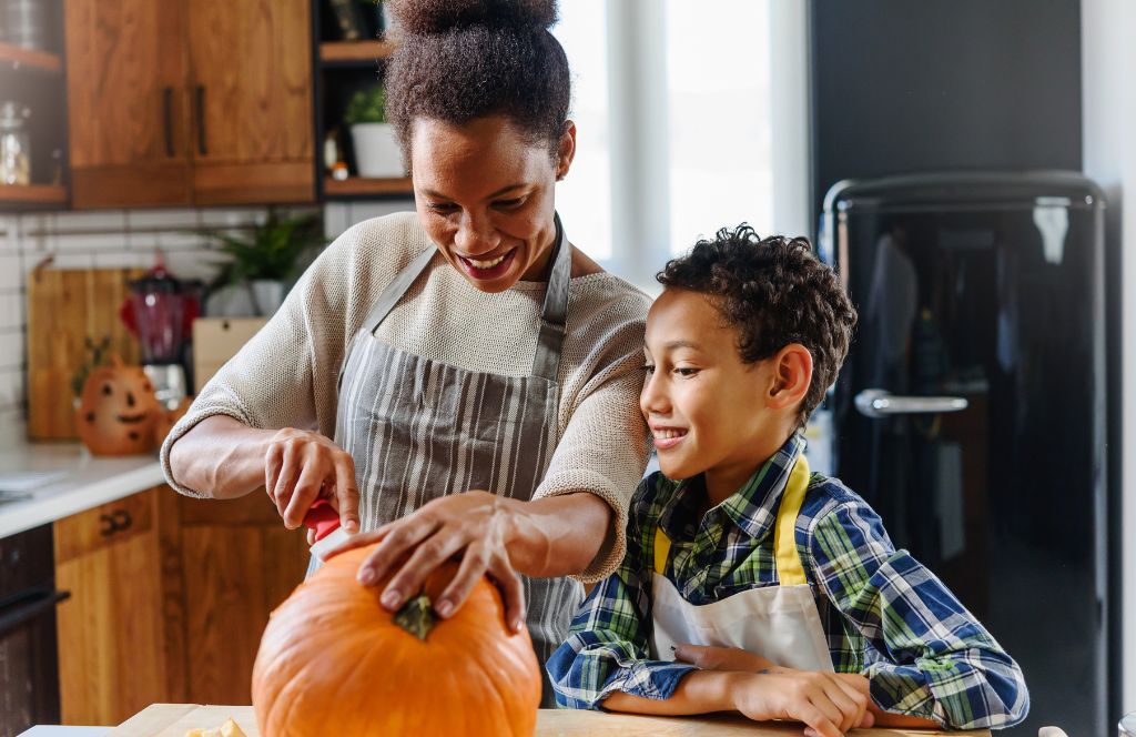 een moeder en zoon maken pompoensnijwerk als leuke halloweenactiviteit