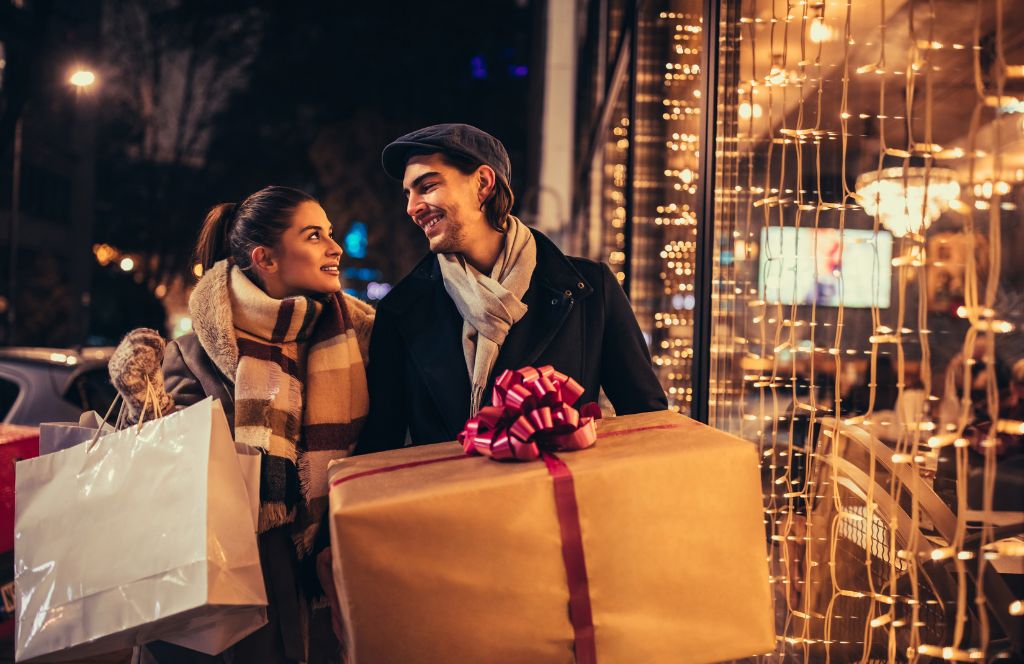 un hombre y una mujer van de compras navideñas por la noche