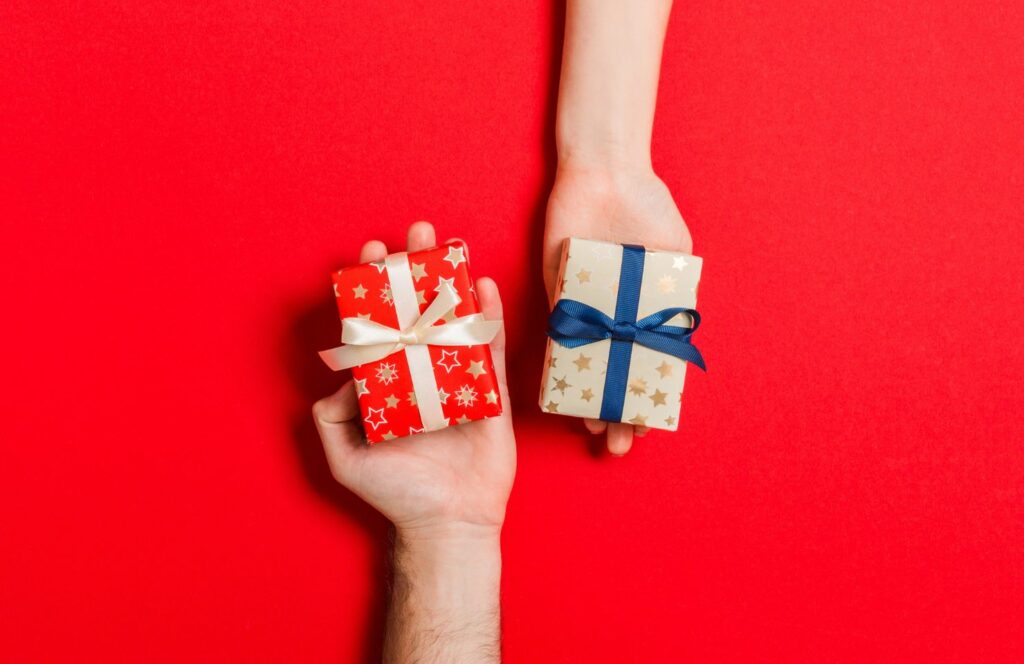 3 mains offrant un cadeau lors d'un jeu pour ouvrir les cadeaux de Noël