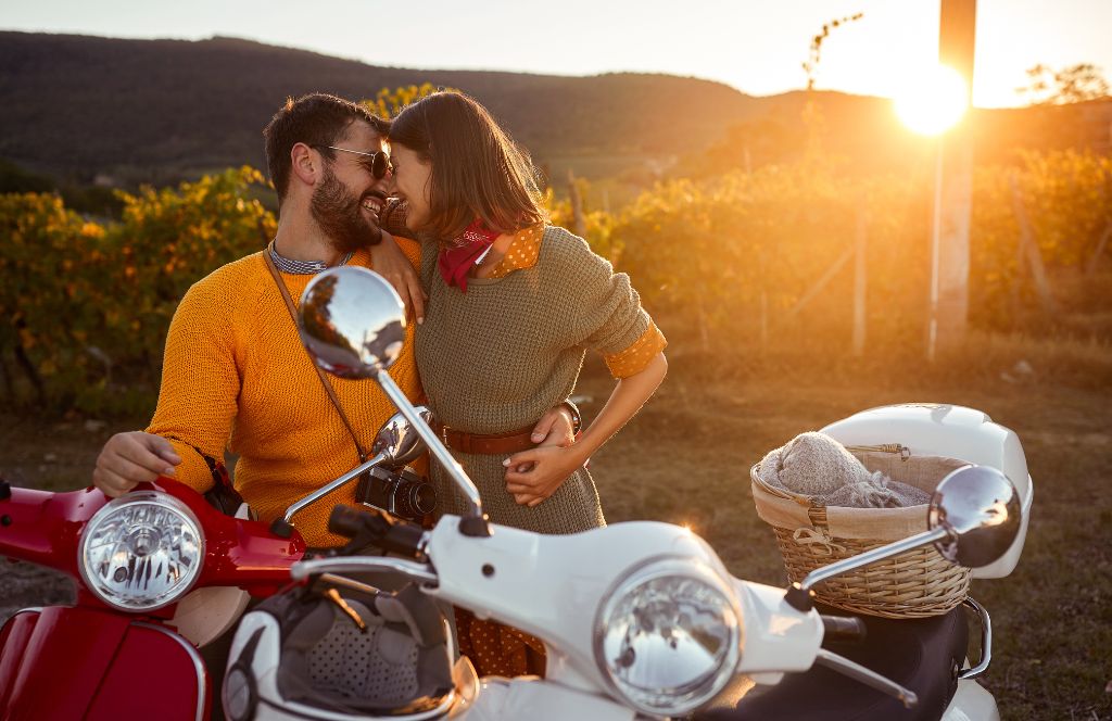 couple riding a vespa through italy 